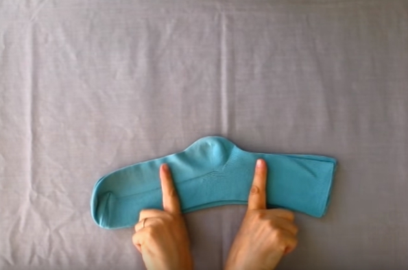 Автор видео показывает, как сложить носки в аккуратный и плоский прямоугольник